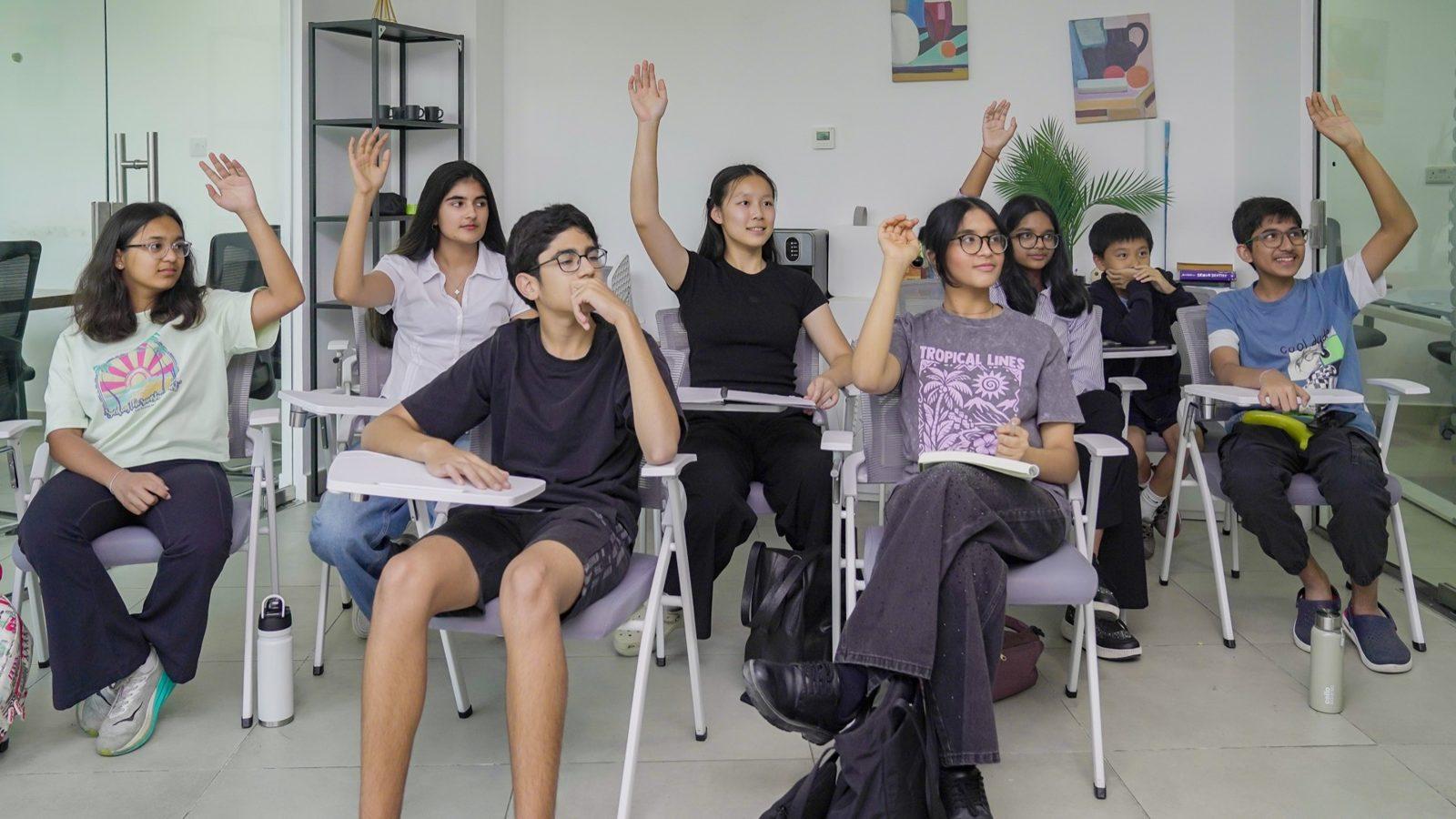 A room of students with hands raised during a live class discussion