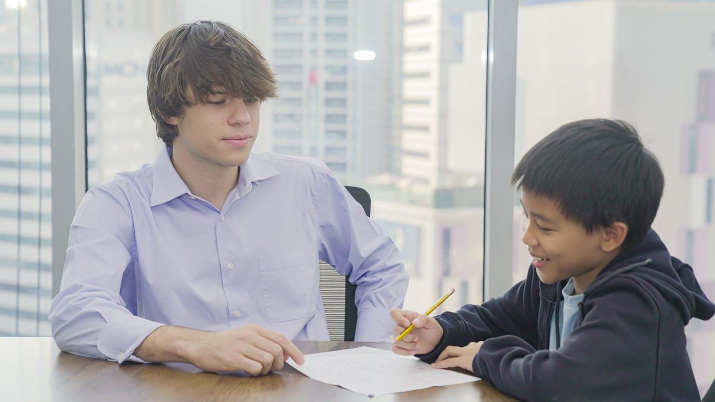 A coach works through a draft with a younger student